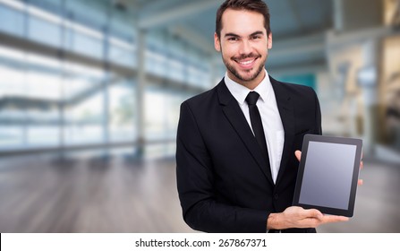Smiling businessman showing his tablet pc against fitness studio