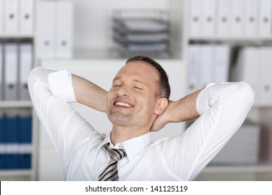 Smiling businessman sitting and relaxing at the office