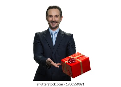 Smiling businessman in suit giving a present. Joyful middle-aged boss holding a gift. Successful formal-dressed man isolated on white background. - Shutterstock ID 1780559891
