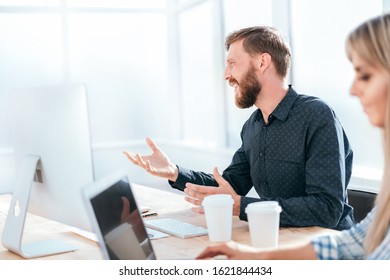 smiling businessman talking to a colleague sitting at his Desk