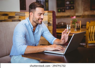 Smiling businessman using his laptop at the cafe - Shutterstock ID 294791732