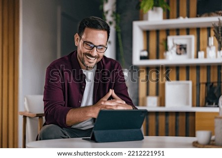 Smiling businessman working online, from home, over the tablet.