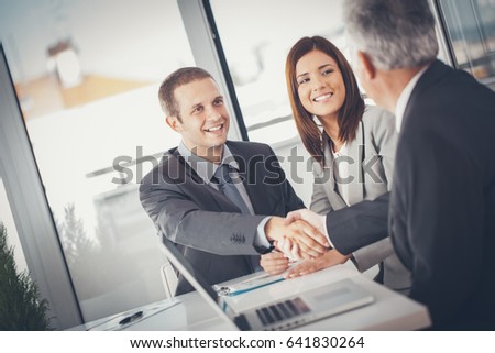 Smiling businessmen shaking hands after closing a deal.
