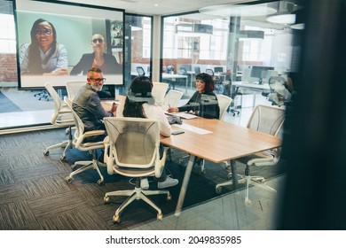 Smiling Businesspeople Having A Virtual Meeting With Their Associates. Group Of Creative Businesspeople Attending A Meeting In A Boardroom. Team Of Businesspeople Communicating With Their Partners.