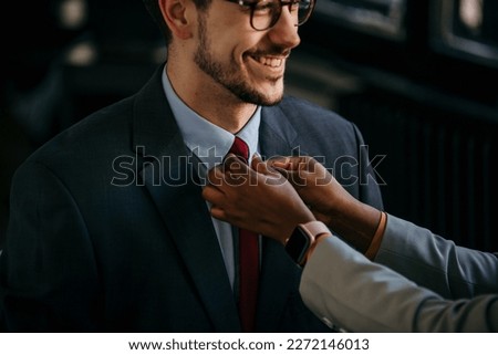Smiling businesswoman adjusting businessman tie.