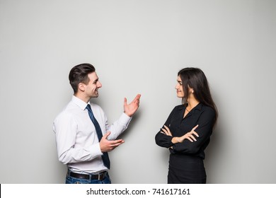 Smiling businesswoman and businessman are conversing against grey