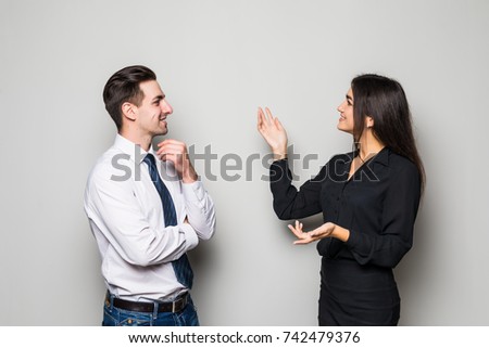 Smiling businesswoman and businessman are conversing against grey