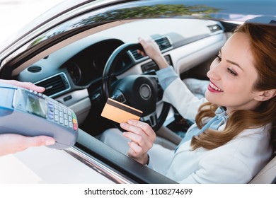 Smiling Businesswoman In Car Making Payment With Credit Card