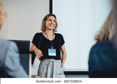 Smiling businesswoman delivering a speech during a conference. Successful business professional giving presentation. - Powered by Shutterstock