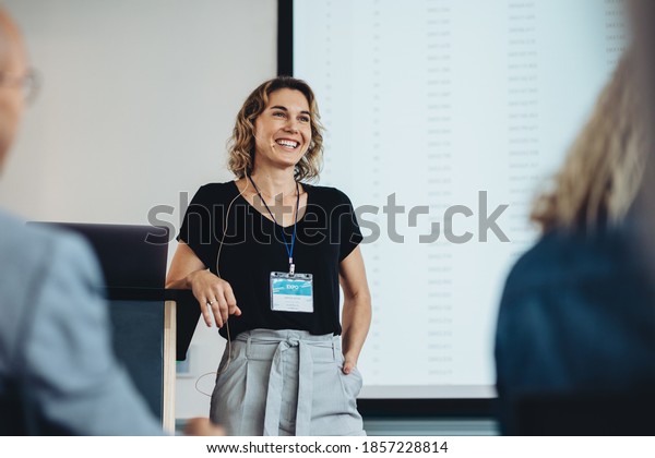 Smiling\
businesswoman delivering a speech during a conference. Successful\
business professional giving\
presentation.