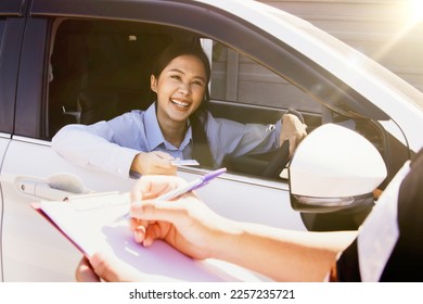 Smiling businesswoman driving car contacts security guard and presents ID card to show her identity for entry exit security officer record the information in the area as evidence with good standing. - Shutterstock ID 2257235721