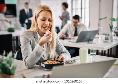 Smiling Businesswoman Eating Healthy Food At Work And Having Vegetable Salad For Lunch.