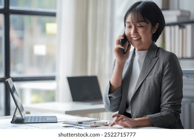 Smiling businesswoman having phone call and analyzing financial charts in modern office - Powered by Shutterstock