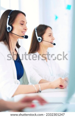 Smiling businesswoman or helpline operator with headset and computer at office