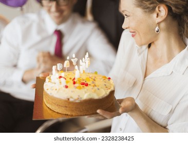 Smiling businesswoman holding birthday cake with candles - Powered by Shutterstock