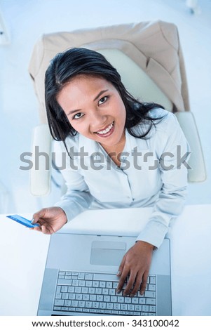 Smiling businesswoman holding credit card at the desk in work