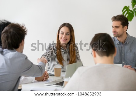 Smiling businesswoman shaking hand of male partner at negotiations, friendly woman handshaking man greeting new team member at group meeting, respect or first impression, making business deal concept