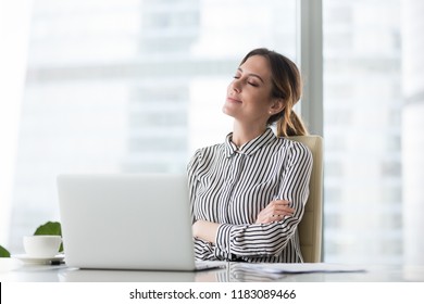 Smiling businesswoman sitting in office chair relaxing with eyes closed, calm female worker or woman ceo feeling peaceful resting at workplace dreaming about positive things distracted from work - Powered by Shutterstock