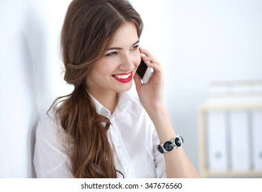 Smiling businesswoman talking on phone sitting at the office - Shutterstock ID 347676560