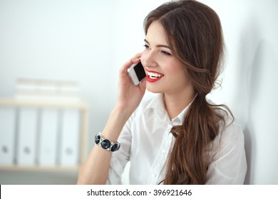Smiling businesswoman talking on the phone at the office - Shutterstock ID 396921646