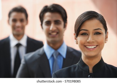 smiling businesswoman, two businessman in background