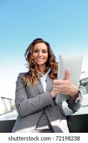Smiling businesswoman using electronic tablet outside - Shutterstock ID 72198238