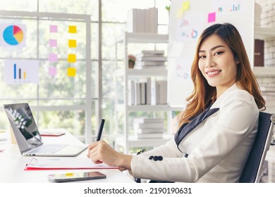 Smiling Businesswoman Working On Her Computer At Her Desk Inside Modern Office. Happy Asian Woman With Successful Smile In Her Work.