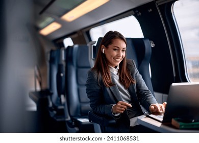 Smiling businesswoman working on laptop while commuting by train. Copy space. - Powered by Shutterstock