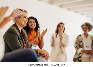 Smiling businesswomen applauding their colleague during a conference meeting in a modern workplace. Group of successful businesswomen working together in an all-female startup. - Shutterstock ID 2152914997