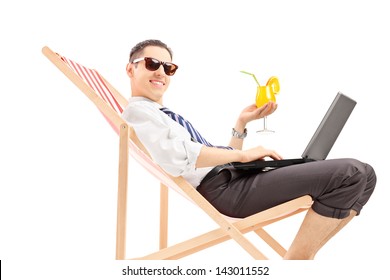 Smiling Busy Man With Laptop Sitting On A Beach Chair And Holding A Cocktail, Isolated On White Background