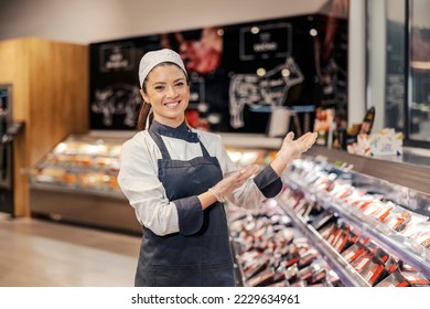 A smiling butcher is welcoming customers to a meat department at supermarket and smiling at the camera. - Powered by Shutterstock