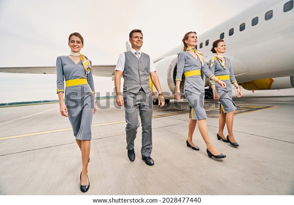 Smiling cabin crew\
in uniforms walking\
ahead