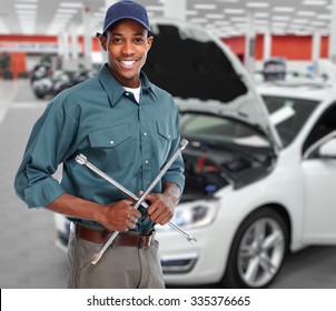 Smiling car mechanic with wrench in auto repair service. 