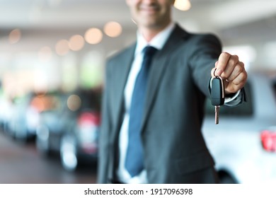 Smiling car salesman handing over your new car keys, dealership and sales concept - Shutterstock ID 1917096398