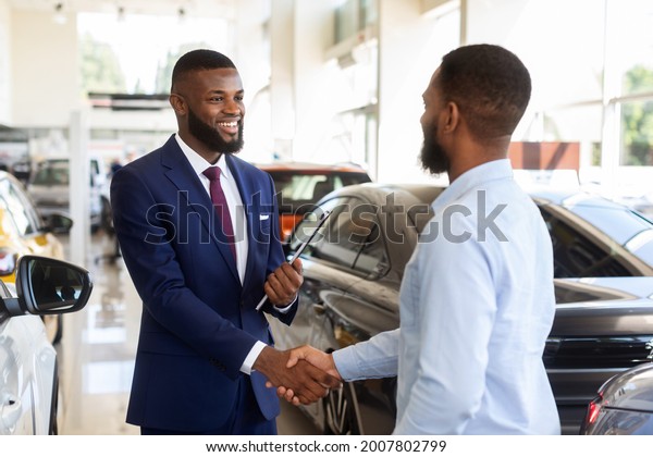 Smiling Car Seller Shaking Hands With Client\
After Successful Deal, Happy African American Man Buying New\
Vehicle In Dealership Center, Making Agreement With Salesperson In\
Modern Auto Showroom