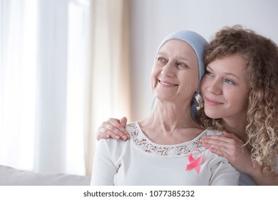 Smiling Caregiver Hugging A Senior Woman With Cancer Wearing A Pink Ribbon