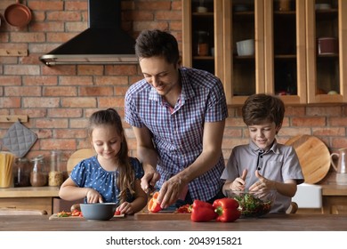 Smiling caring young father teaching small children siblings preparing healthy vegan food, chopping fresh vegetables for salad together in kitchen. Happy family daddy and kids cooking at home. - Powered by Shutterstock