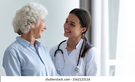 Smiling caring young female nurse doctor caretaker assisting happy senior grandma helping old patient in rehabilitation recovery at medical checkup visit, elder people healthcare homecare concept - Shutterstock ID 1562123116