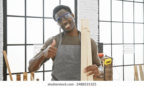 Smiling carpenter with safety glasses giving thumbs up in a well-lit workshop - Powered by Shutterstock