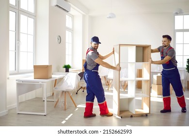 Smiling carriers help customer with furniture during relocation and moving day. Deliverymen or movers in uniform carry shelves work for client at office or new home settle. Transportation concept. - Shutterstock ID 2152662593