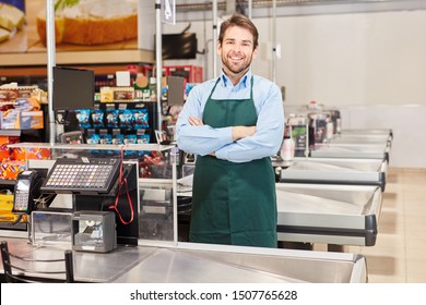 Smiling cashier or salesman in green apron at the supermarket cashier - Powered by Shutterstock