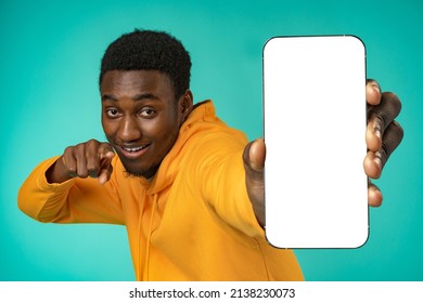 Smiling Casual Black Man Pointing At Blank White Cell Phone Screen In Studio