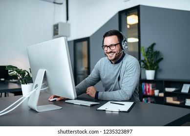 Smiling Casual Business Man With Headset Working On The Computer.