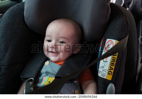 Smiling\
Caucasian 4 month old baby sitting in baby carrier safety car seat.\
child safety transport. family trips.\
holidays