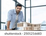 Smiling caucasian architect engineer looking at camera while standing with house model. Smart interior designer standing while holding pencil. Project plan, civil engineering, worker. Tracery.