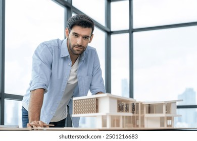 Smiling caucasian architect engineer looking at camera while standing with house model. Smart interior designer standing while holding pencil. Project plan, civil engineering, worker. Tracery. - Powered by Shutterstock