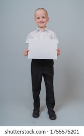 Smiling Caucasian Boy 7 Years Old Stay And Holding A Blank Sheet Of Paper