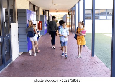 Smiling caucasian of boy and girl holding books, walking in school corridor talking copy space. Education, inclusivity, elementary school and learning concept. - Powered by Shutterstock