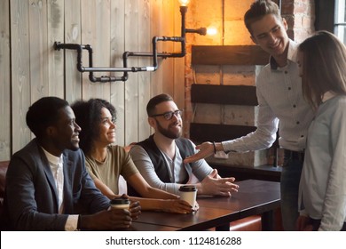 Smiling Caucasian Boyfriend Introducing Multiracial Friends To Girlfriend At Meeting In Coffeeshop, Millennial Male Acquainting Diverse Colleagues With Female Worker In Cafe. First Impression Concept