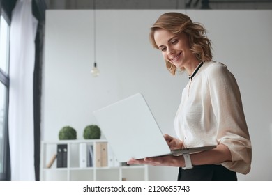 Smiling caucasian businesswoman watching on laptop computer during work at office. Concept of modern successful woman. Idea of business and entrepreneur lifestyle. Attractive girl wearing formal wear